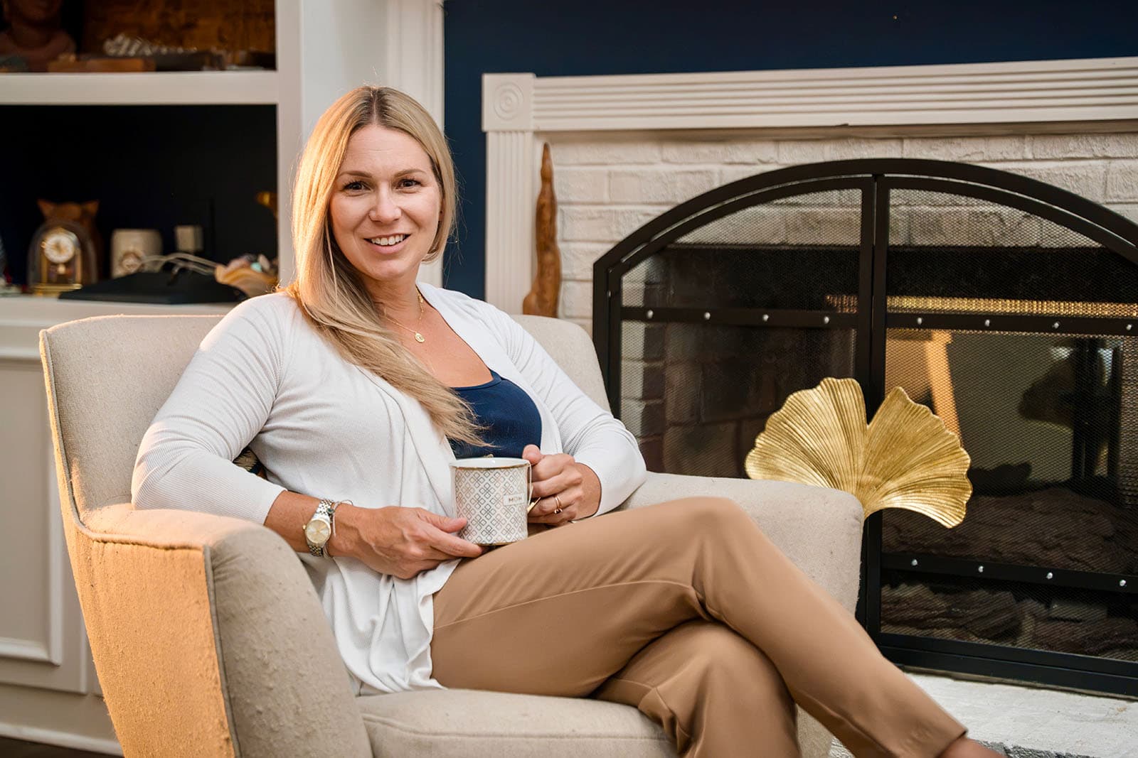 Katherine Weaver with coffee sitting by fireplace
